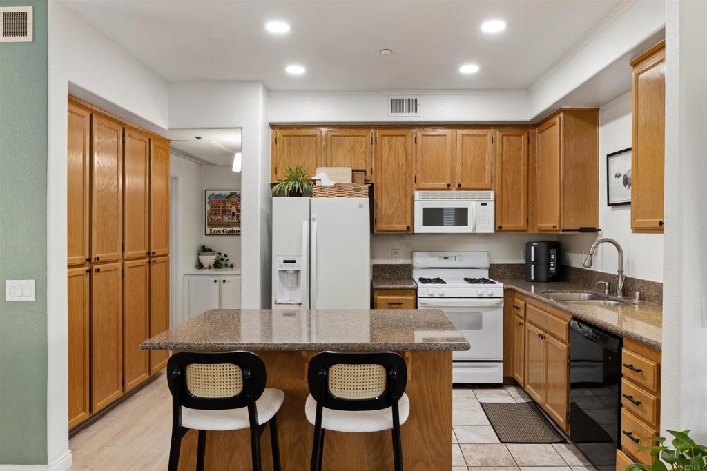 3183 Dehesa Road, Unit 19 El Cajon, CA 92019 - Photo 8 of 26 a kitchen with stainless steel appliances granite countertop a refrigerator a stove a sink dishwasher and white cabinets with wooden floor