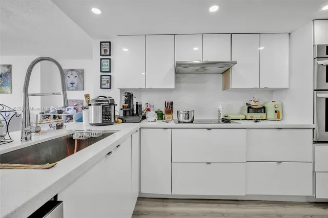 a kitchen with stainless steel appliances granite countertop a sink a stove and cabinets