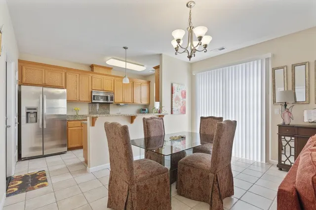 a dining room with furniture a chandelier a kitchen view and a refrigerator