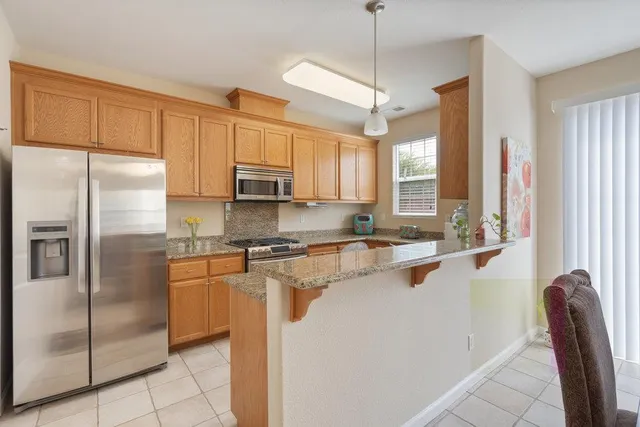 a kitchen with stainless steel appliances granite countertop a refrigerator a sink a stove and white cabinets with wooden floor