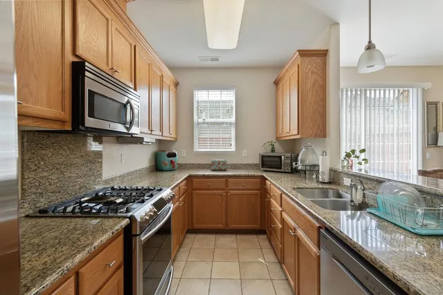 a kitchen with stainless steel appliances granite countertop a sink stove and cabinets
