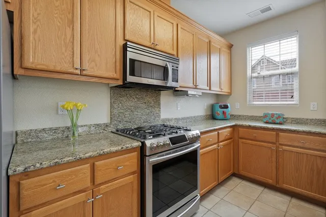 a kitchen with granite countertop stainless steel appliances white cabinets granite counter tops and a wooden floors
