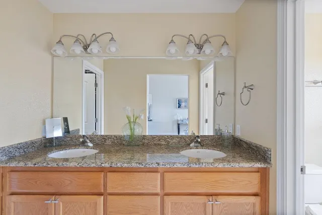 a bathroom with a granite countertop sink a mirror and shower