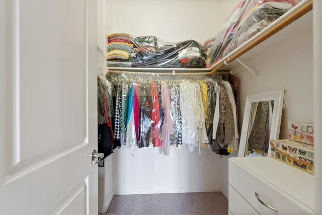 a view of walk in closet with clothes and shoes