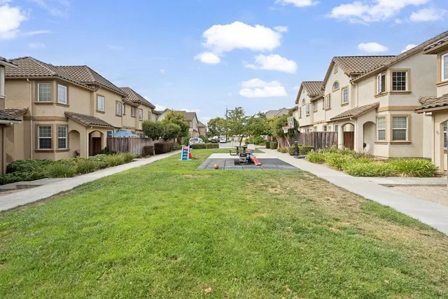 a view of a white house with a big yard and potted plants