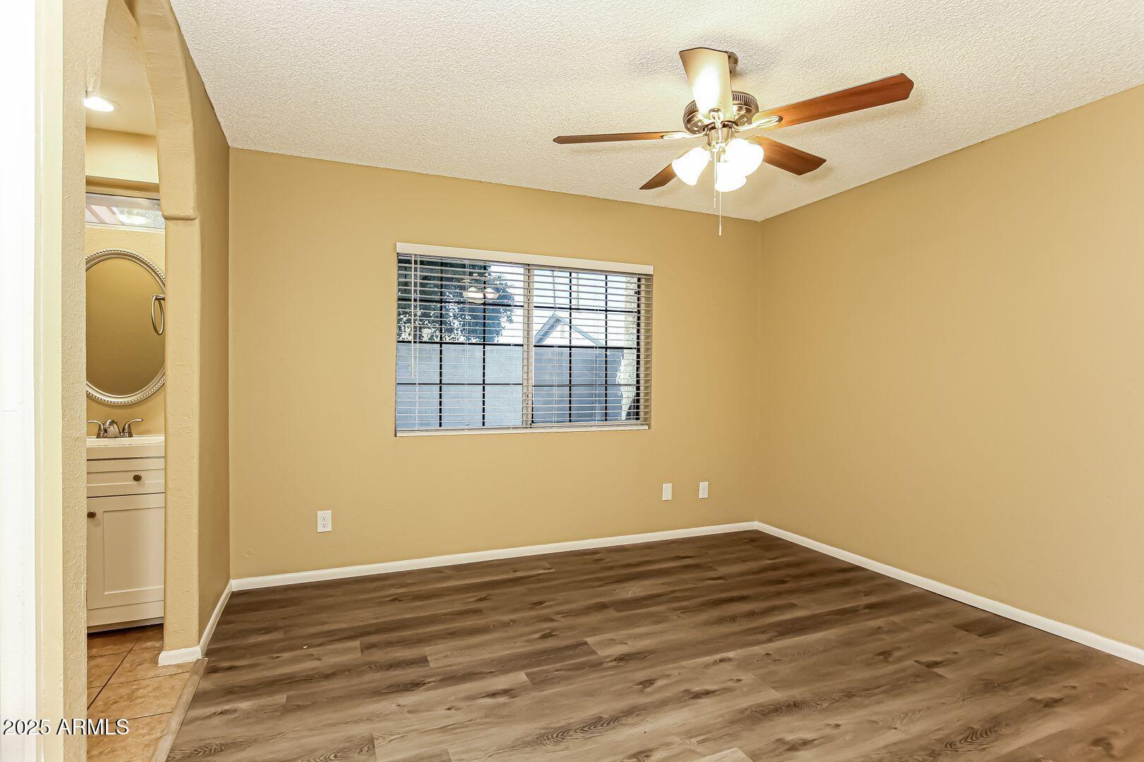 4610 North 75th Drive Phoenix, AZ 85033 - Photo 7 of 14 an empty room with a window and wooden floor