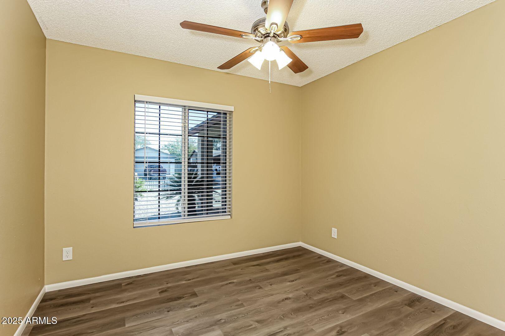 4610 North 75th Drive Phoenix, AZ 85033 - Photo 9 of 14 a view of an empty room with wooden floor and a window
