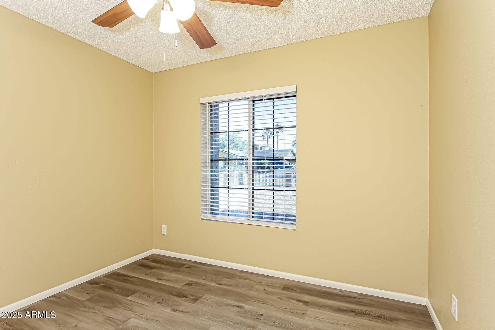 4610 North 75th Drive Phoenix, AZ 85033 - Photo 10 of 14 an empty room with a window and wooden floor
