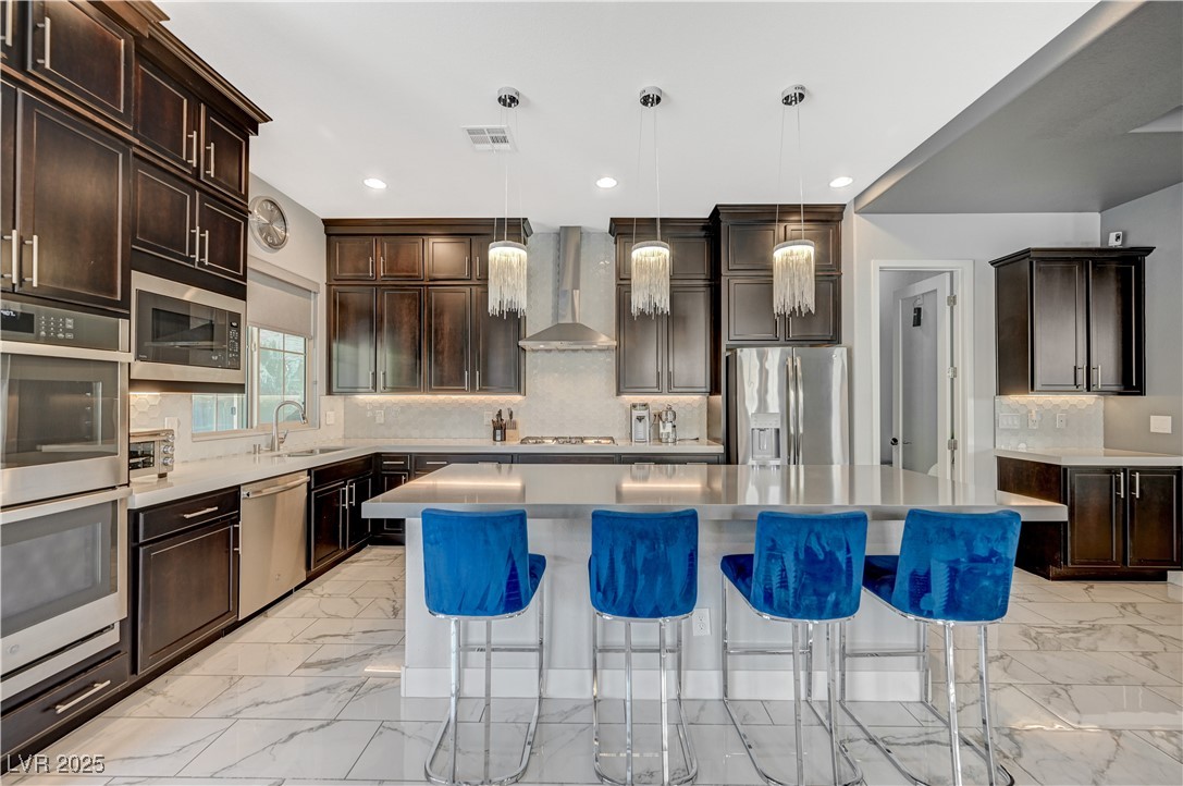 3943 Reyes Avenue Las Vegas, NV 89141 - Photo 13 of 93 Kitchen with decorative backsplash, light marble finish flooring, dark brown cabinets, pendant lighting, and recessed lighting