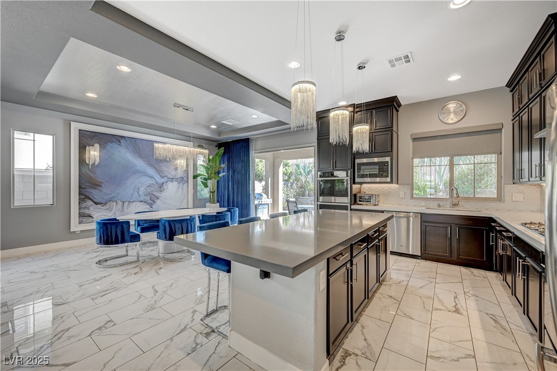 3943 Reyes Avenue Las Vegas, NV 89141 - Photo 15 of 93 Kitchen featuring a raised ceiling, a kitchen breakfast bar, light marble finish flooring, and recessed lighting