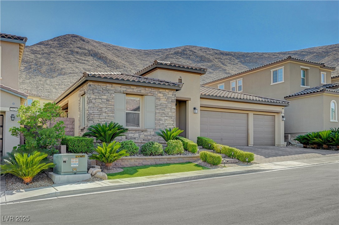 3943 Reyes Avenue Las Vegas, NV 89141 - Photo 3 of 93 Mediterranean / spanish-style house featuring a garage, stone siding, stucco siding, a mountain view, and driveway