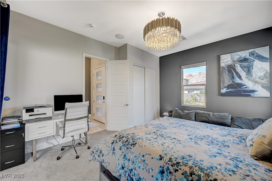 3943 Reyes Avenue Las Vegas, NV 89141 - Photo 43 of 93 Bedroom featuring light carpet, a chandelier, a desk, and a closet