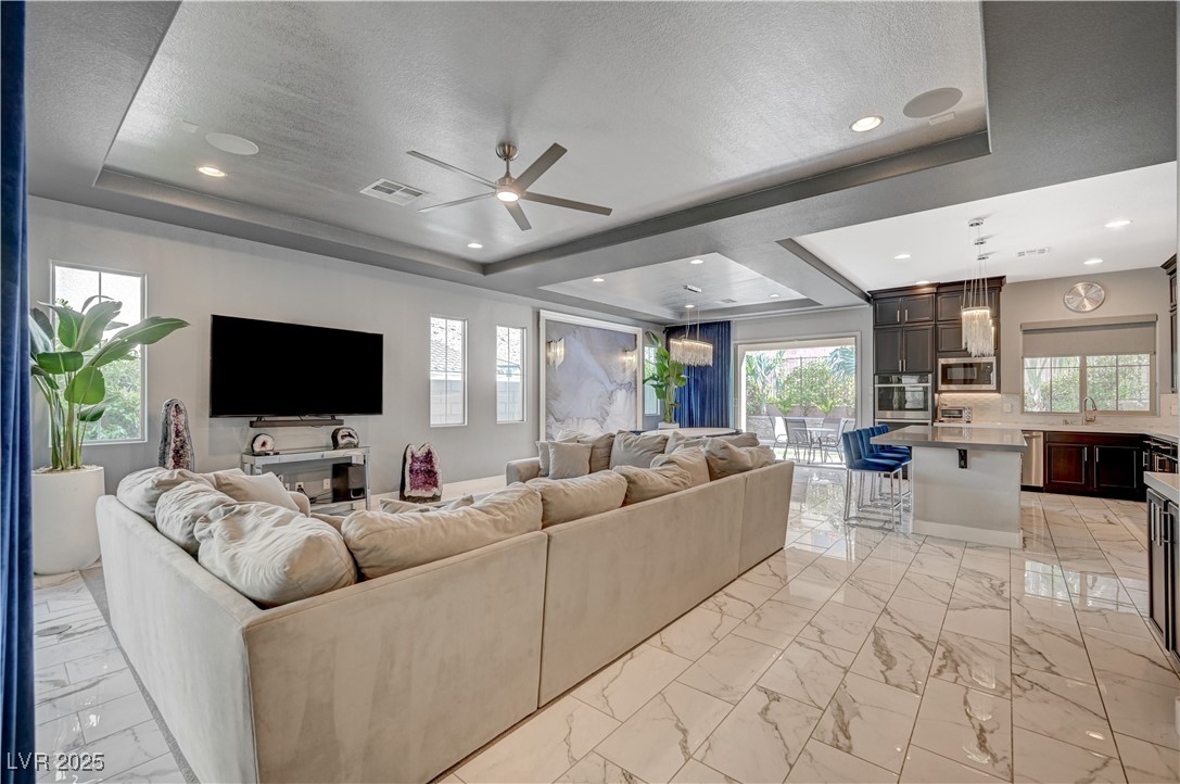 3943 Reyes Avenue Las Vegas, NV 89141 - Photo 5 of 93 Living room with a raised ceiling, light marble finish flooring, a ceiling fan, recessed lighting, and a textured ceiling