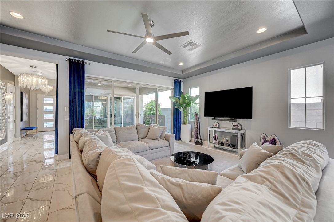 3943 Reyes Avenue Las Vegas, NV 89141 - Photo 7 of 93 Living room with marble look tile flooring, a tray ceiling, a ceiling fan, recessed lighting, and a textured ceiling