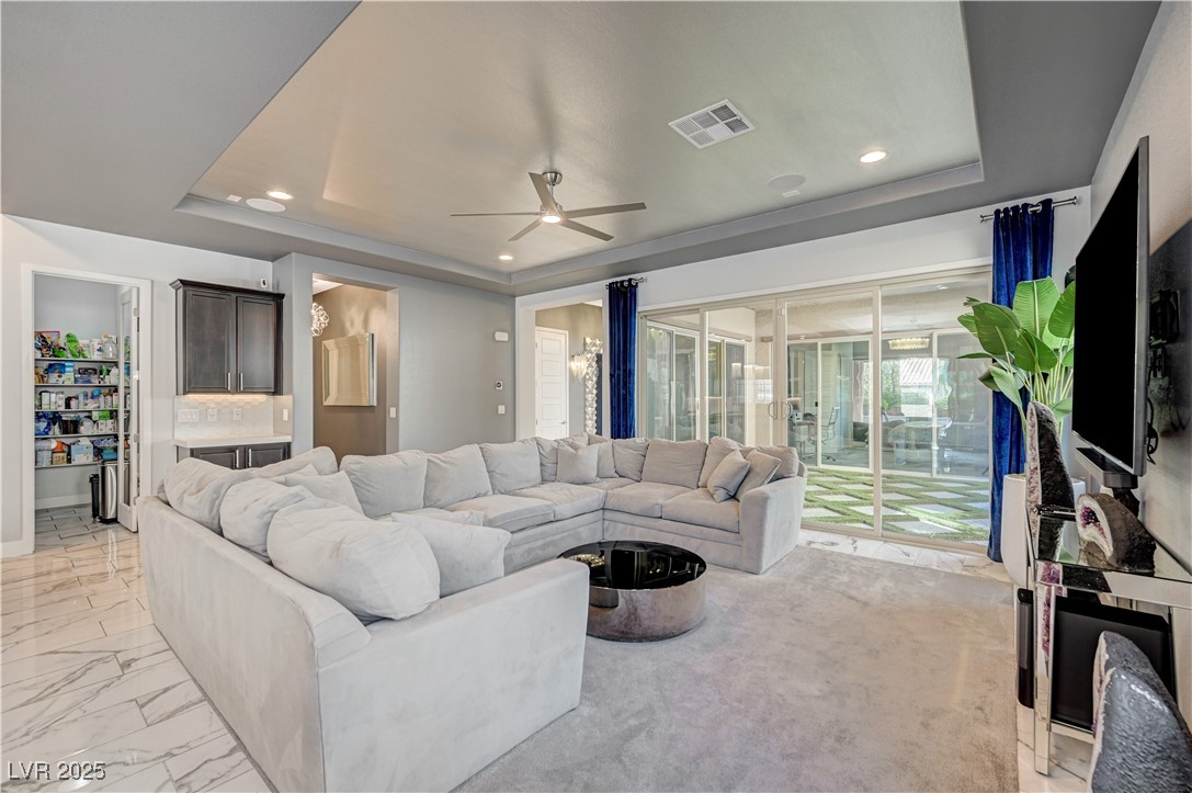 3943 Reyes Avenue Las Vegas, NV 89141 - Photo 8 of 93 Living area featuring a tray ceiling, recessed lighting, a ceiling fan, and light marble finish floors