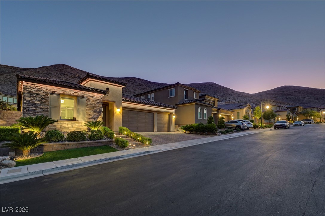 3943 Reyes Avenue Las Vegas, NV 89141 - Photo 79 of 93 View of front facade featuring stone siding, stucco siding, a garage, a mountain view, and driveway
