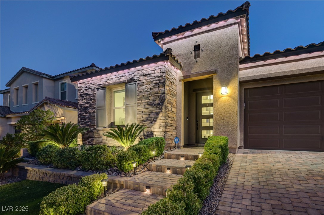 3943 Reyes Avenue Las Vegas, NV 89141 - Photo 81 of 93 Mediterranean / spanish house featuring stone siding, a garage, stucco siding, decorative driveway, and a tiled roof