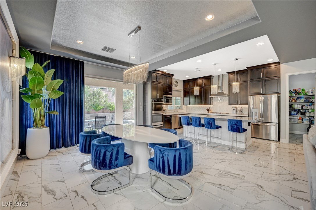 3943 Reyes Avenue Las Vegas, NV 89141 - Photo 10 of 93 Kitchen featuring dark brown cabinets, appliances with stainless steel finishes, a center island, light marble finish floors, and recessed lighting