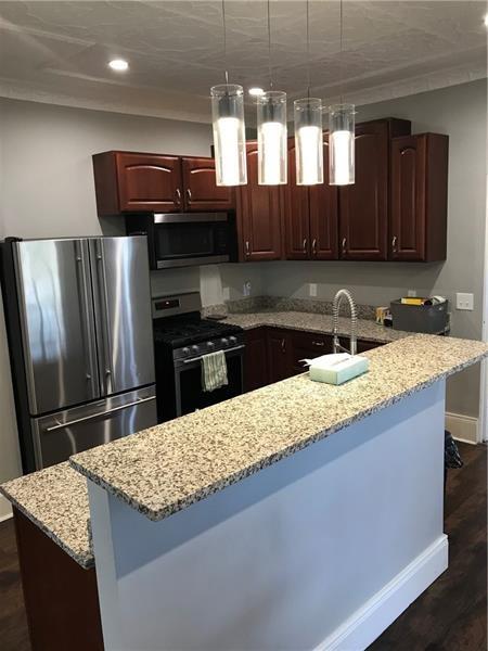 1124 Brabec Street Pittsburgh, PA 15212 - Photo 3 of 11 a kitchen with granite countertop a sink a stove top oven a refrigerator and a cabinets