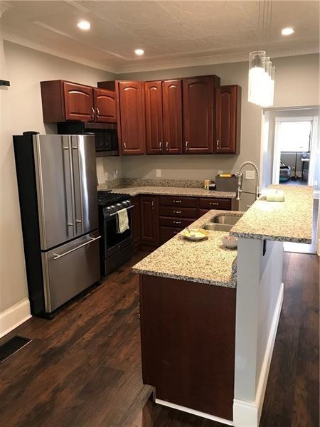 1124 Brabec Street Pittsburgh, PA 15212 - Photo 4 of 11 a kitchen with granite countertop wooden cabinets a refrigerator and a sink