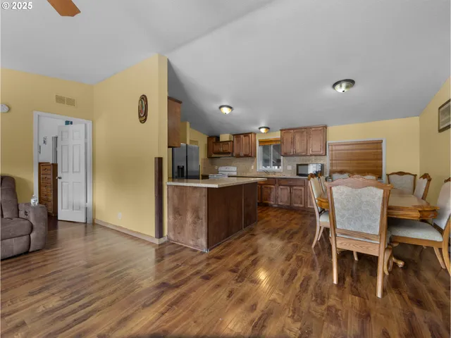 a kitchen with stainless steel appliances kitchen island granite countertop a refrigerator a stove a sink dishwasher with a dining table and chairs