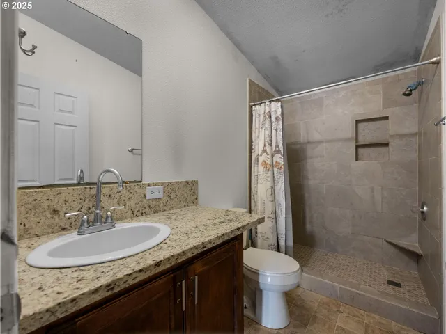 a bathroom with a granite countertop sink toilet and shower