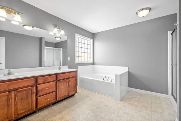 a spacious bathroom with a tub sink and mirror