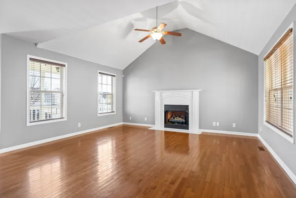 an empty room with windows fireplace and wooden floor