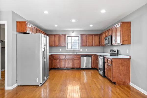 a kitchen with stainless steel appliances granite countertop a refrigerator sink and wooden cabinets