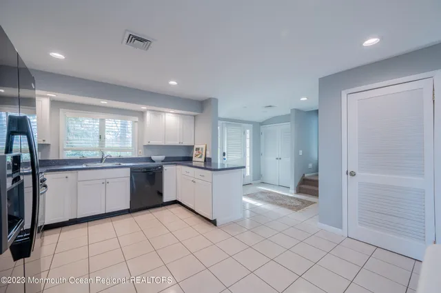 a large white kitchen with a sink and dishwasher a refrigerator with wooden cabinets