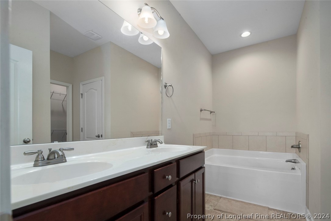 3631 Thrower Road Hope Mills, NC 28348 - Photo 30 of 50 a bathroom with a tub a double vanity sink and a mirror