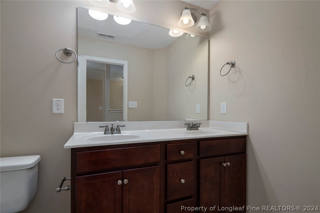 3631 Thrower Road Hope Mills, NC 28348 - Photo 41 of 50 a bathroom with a double vanity sink a toilet and a mirror