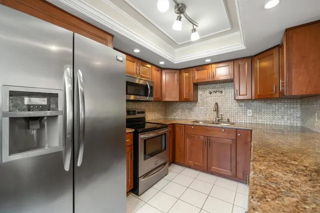 a kitchen with stainless steel appliances granite countertop a sink a stove a refrigerator cabinets and a dining table