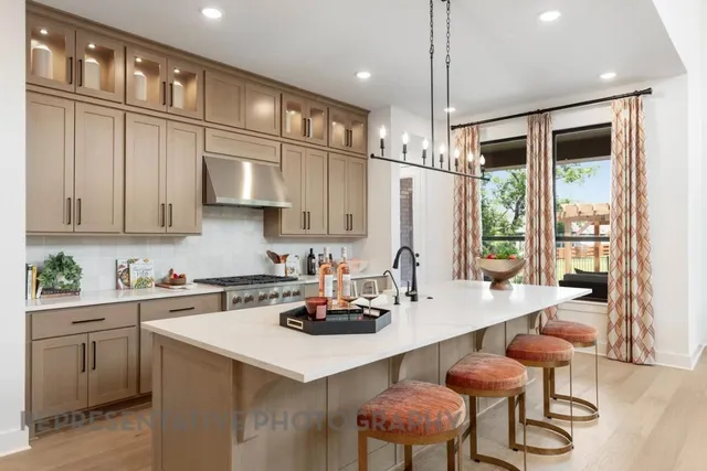 a kitchen with stainless steel appliances a sink a stove a refrigerator cabinets and dining table