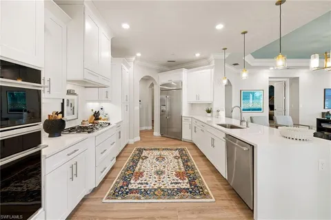 a large white kitchen with lots of counter space a sink appliances and cabinets