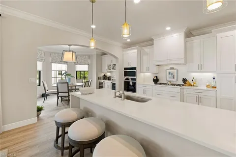 a kitchen with stainless steel appliances kitchen island granite countertop a sink a stove a dining table and chairs with wooden floor