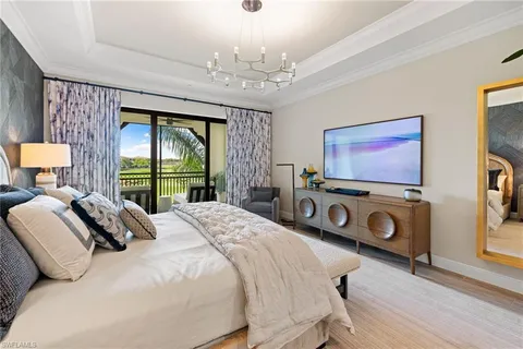 a bedroom with a bed and a flat tv screen on dresser