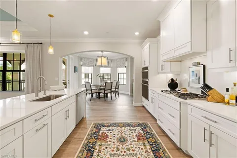 a large white kitchen with lots of counter space and wooden floor