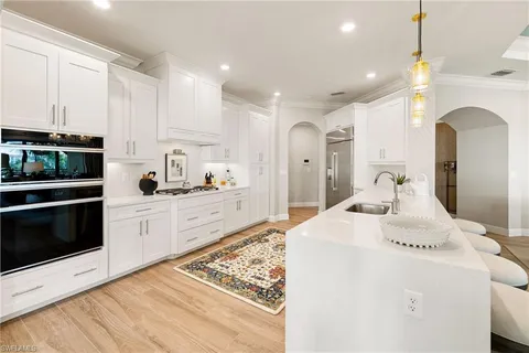 a large white kitchen with kitchen island a sink stainless steel appliances and cabinets