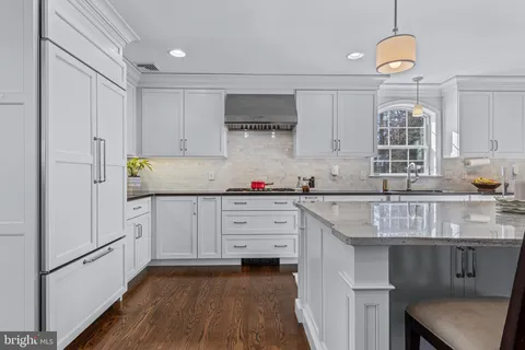 a kitchen with stainless steel appliances kitchen island granite countertop a table chairs sink and cabinets