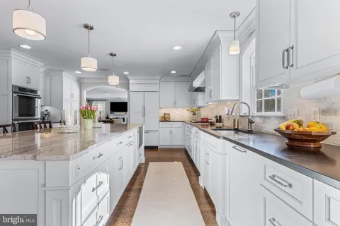 a kitchen with a dining table chairs wooden floor cabinets and appliances