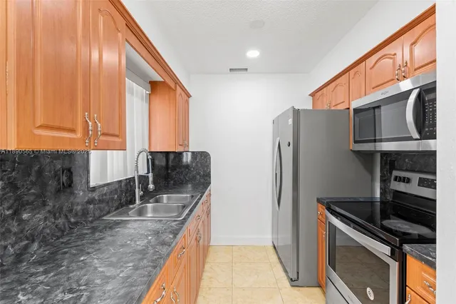a kitchen with stainless steel appliances granite countertop a refrigerator a stove and a sink with wooden floor