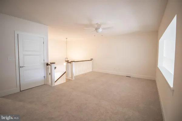 an empty room with an entryway and chandelier fan