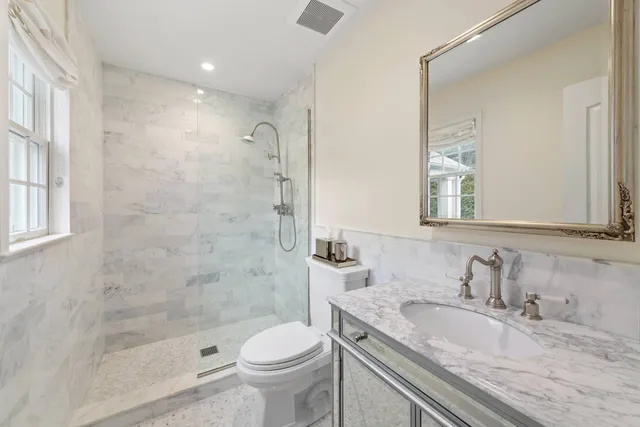 a bathroom with a granite countertop sink a toilet and shower