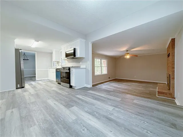 a view of empty room with kitchen and fireplace
