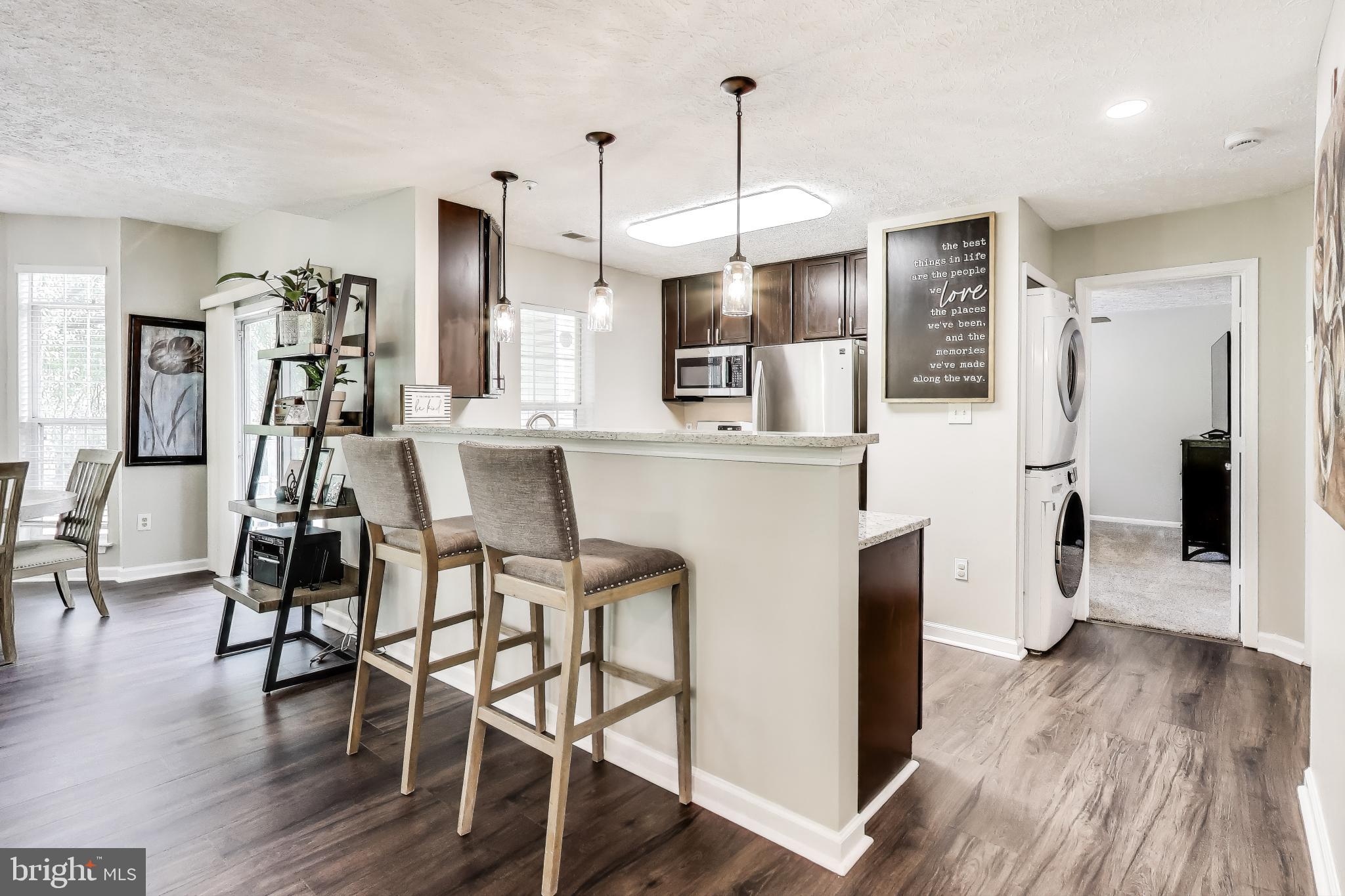 15602 Everglade Lane, Unit 2203 Bowie, MD 20716 - Photo 1 of 24 a kitchen with stainless steel appliances kitchen island wooden floors and refrigerator