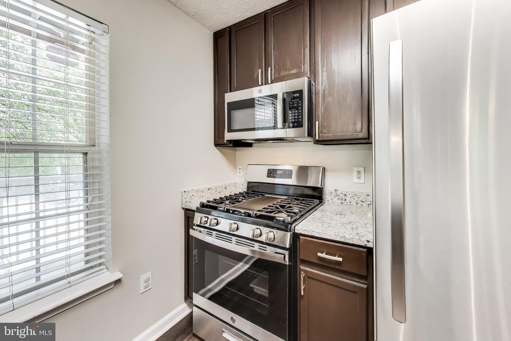 15602 Everglade Lane, Unit 2203 Bowie, MD 20716 - Photo 12 of 24 a kitchen with stainless steel appliances granite countertop a stove and a microwave