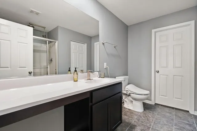 a spacious bathroom with a double vanity sink a toilet and a mirror