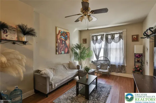a living room with furniture floor to ceiling window and wooden floor