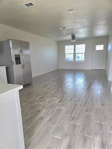 a view of an empty room with window and wooden floor